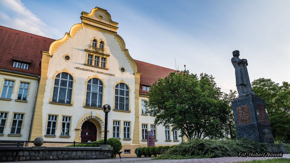 Budynek Starostwa Powiatowego w Złotowie od frontu. Przed nim pomnik Piasta Kołodzieja. Fotografię wykonał Hubert Nowak. Pomnik Piasta Kołodzieja