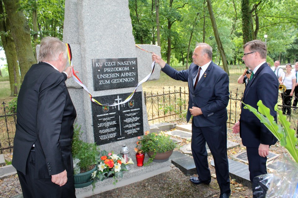 Tablicę umieszczoną na krzyżu znajdującym się na dawnym cmentarzu ewangelickim odsłaniają Ryszard Goławski, dr Andreas Ebel i Rolf-Peter Wachholz Odsłonięcie pamiątkowej tablicy
